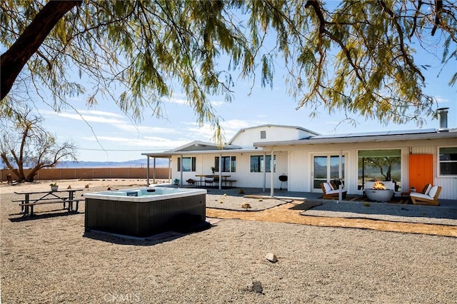 rear view of house featuring a hot tub, fence, and a patio