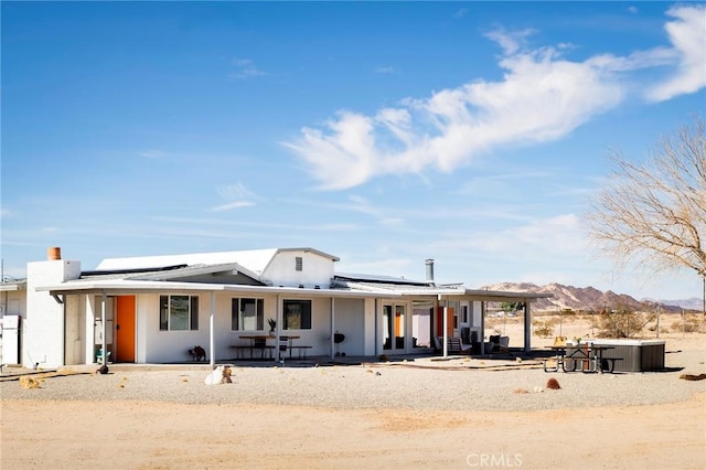 view of front of home with covered porch, solar panels, and a mountain view