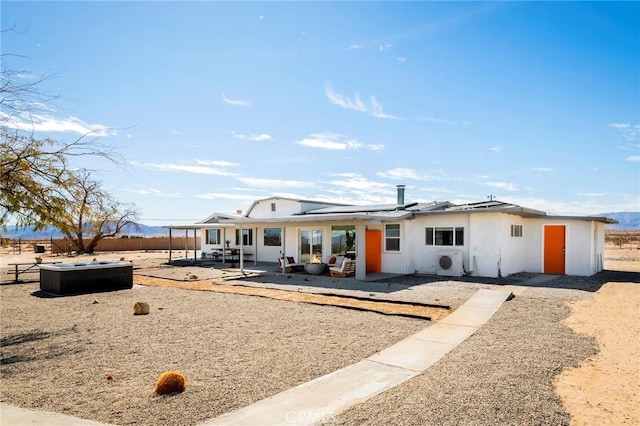 rear view of property featuring a patio area, fence, and roof mounted solar panels