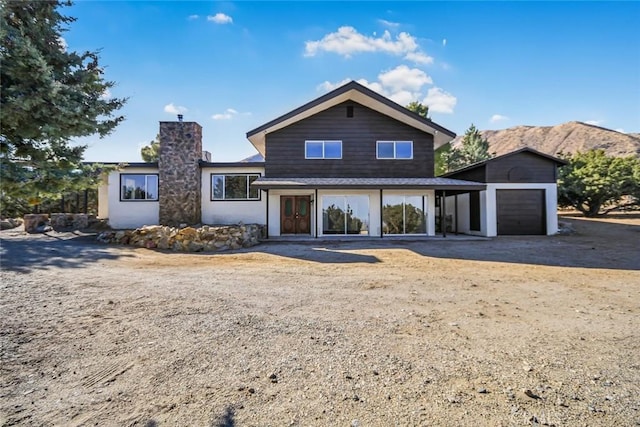 tri-level home with a garage, driveway, a chimney, and a mountain view