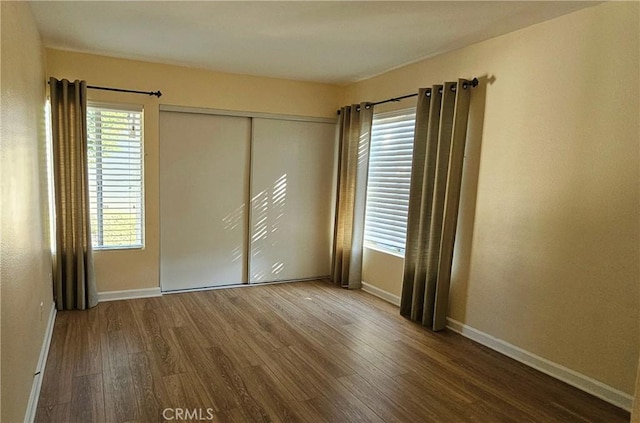 unfurnished bedroom with a closet, baseboards, and wood finished floors