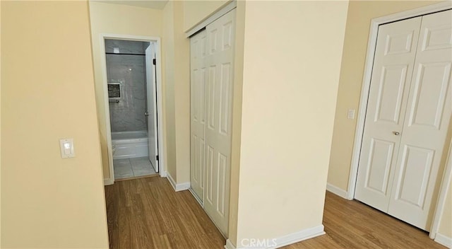 corridor featuring baseboards and wood finished floors