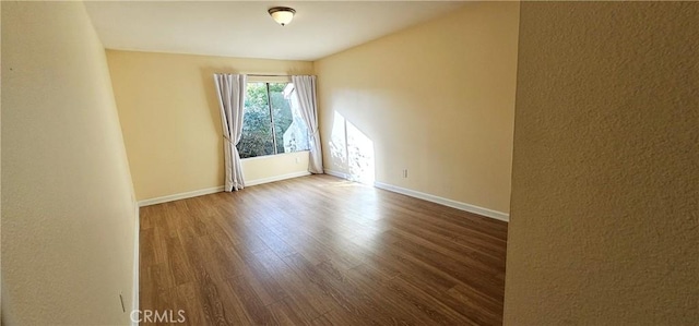 spare room with wood finished floors and baseboards