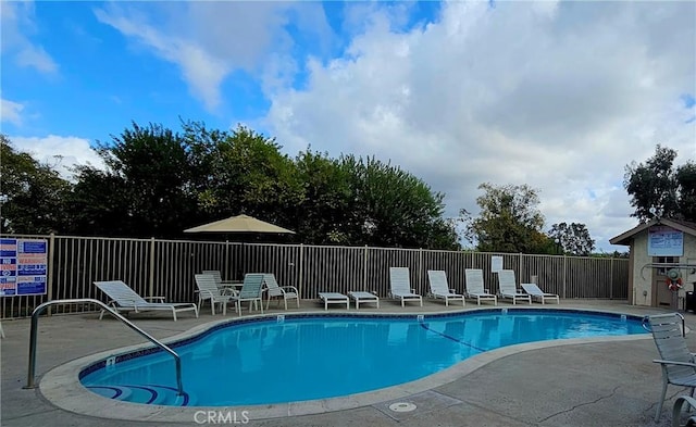 community pool with a patio area and fence