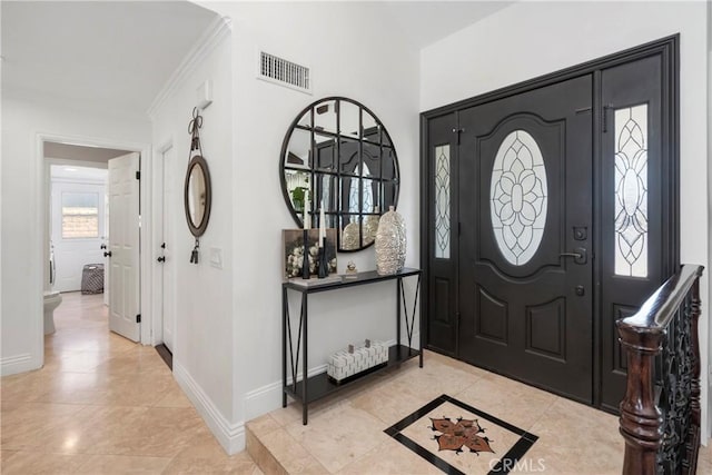 foyer with baseboards, visible vents, and crown molding