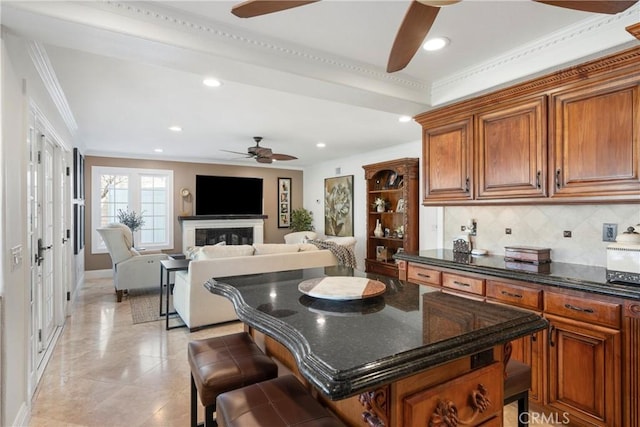 kitchen with ceiling fan, brown cabinetry, and backsplash