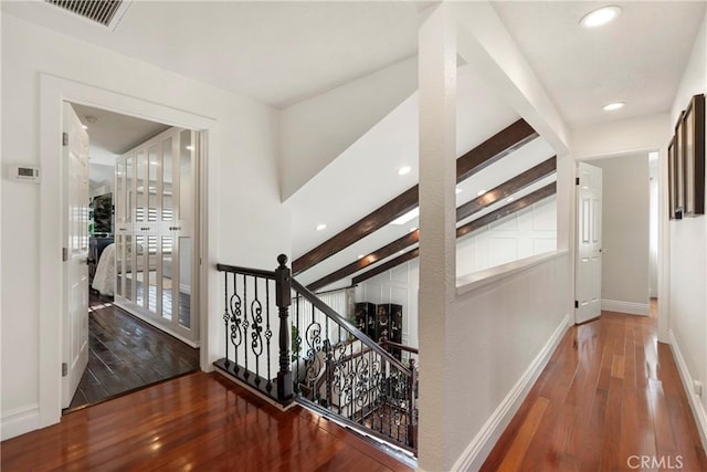 hall featuring baseboards, visible vents, beamed ceiling, and hardwood / wood-style floors