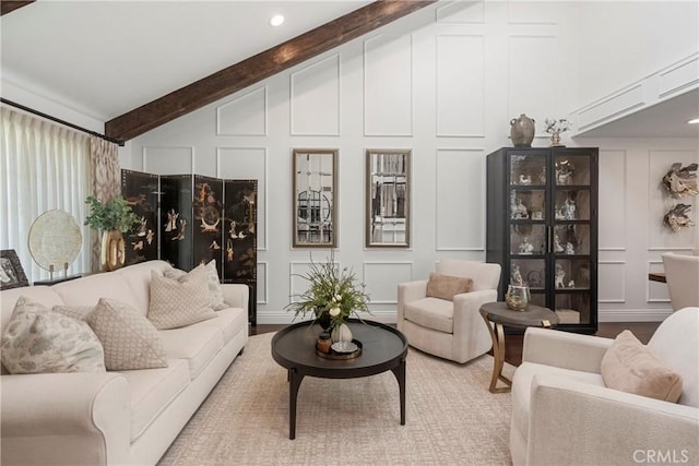 living room featuring vaulted ceiling with beams, a decorative wall, and wood finished floors