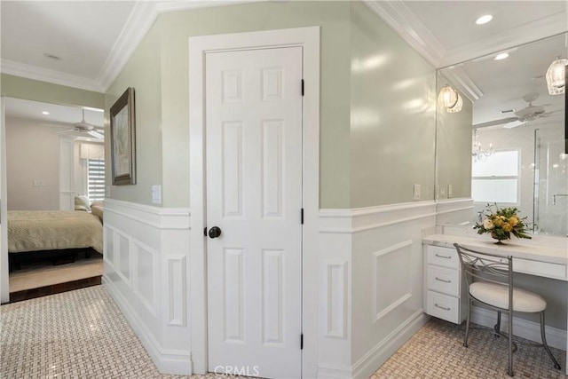 bathroom with ornamental molding, a healthy amount of sunlight, a wainscoted wall, and a decorative wall