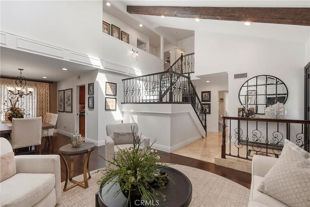 living area featuring wood finished floors, visible vents, stairs, beamed ceiling, and an inviting chandelier