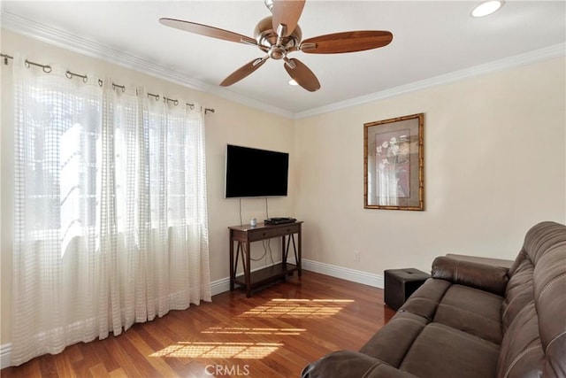 living area featuring ornamental molding, a ceiling fan, baseboards, and wood finished floors