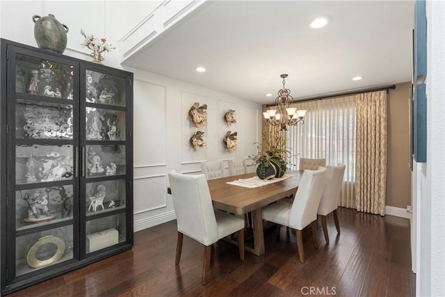 dining area featuring an inviting chandelier, a decorative wall, dark wood finished floors, and recessed lighting