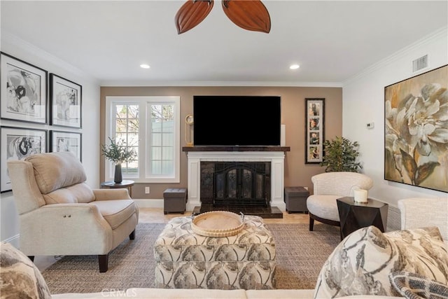 living room with ceiling fan, recessed lighting, visible vents, ornamental molding, and a glass covered fireplace