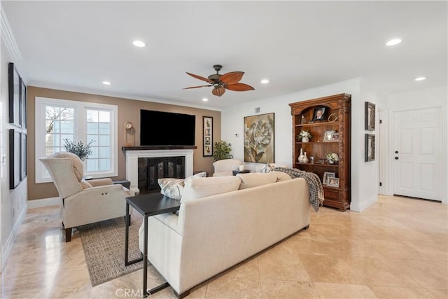 living room with recessed lighting, a glass covered fireplace, and crown molding