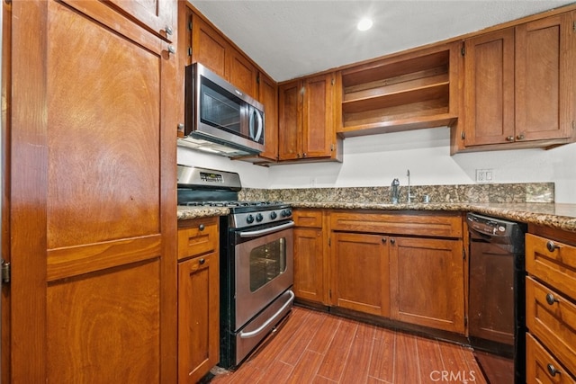 kitchen featuring wood finished floors, a sink, appliances with stainless steel finishes, open shelves, and brown cabinetry