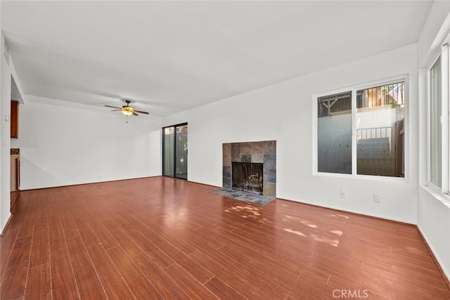 unfurnished living room featuring wood finished floors, a tile fireplace, and a ceiling fan