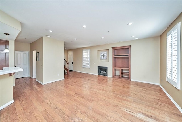 unfurnished living room featuring light wood-style floors, a wealth of natural light, and a fireplace