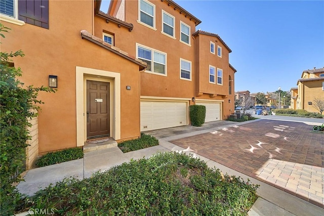 view of front of home with a garage, a residential view, driveway, and stucco siding