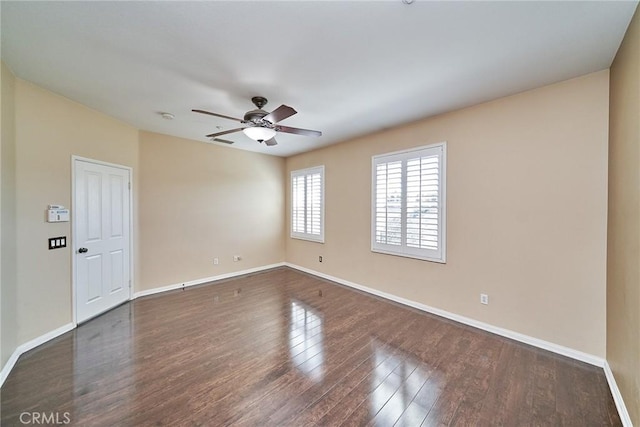 empty room featuring dark wood-style floors, a ceiling fan, and baseboards