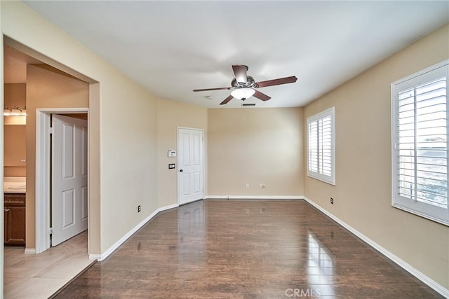 spare room with a ceiling fan, baseboards, and wood finished floors