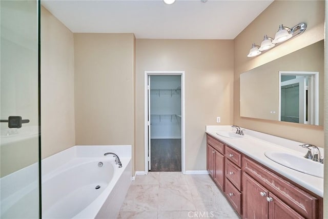 full bathroom featuring a garden tub, marble finish floor, double vanity, and a sink