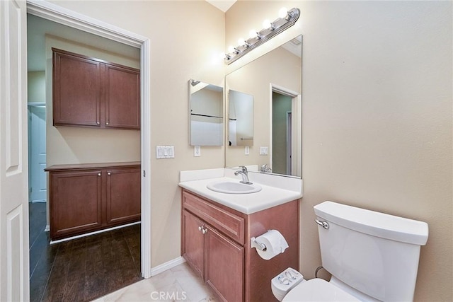 bathroom featuring wood finished floors, vanity, toilet, and baseboards