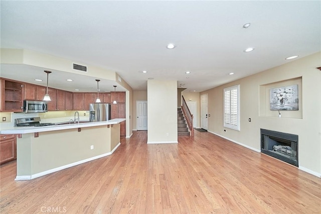 kitchen with a fireplace, visible vents, open floor plan, light countertops, and appliances with stainless steel finishes