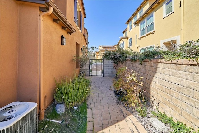 exterior space with a gate, fence, central AC, and stucco siding