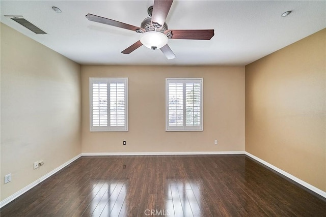 empty room with visible vents, plenty of natural light, baseboards, and wood finished floors