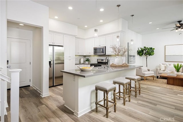 kitchen featuring decorative backsplash, appliances with stainless steel finishes, a breakfast bar, open floor plan, and a sink