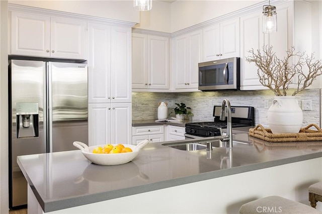 kitchen featuring white cabinets, dark countertops, a breakfast bar, hanging light fixtures, and stainless steel appliances