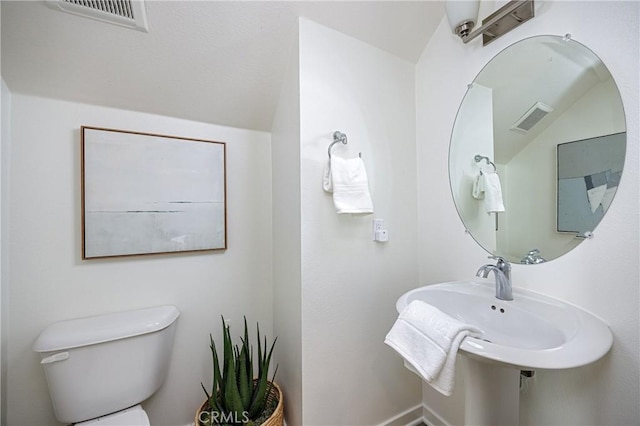 bathroom with lofted ceiling, visible vents, and toilet