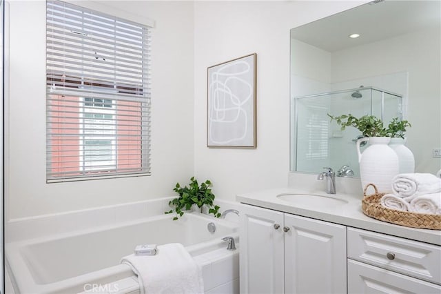 bathroom featuring a stall shower, a garden tub, and vanity