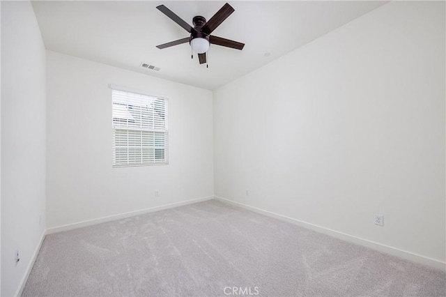 carpeted spare room with baseboards, visible vents, and ceiling fan