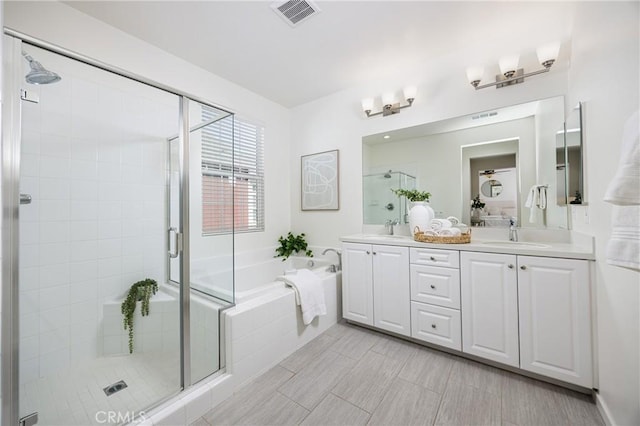 bathroom with a garden tub, double vanity, visible vents, a stall shower, and a sink