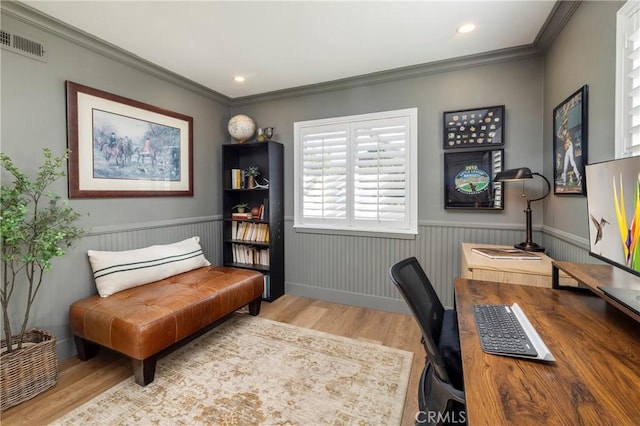 office space with a wainscoted wall, wood finished floors, visible vents, and crown molding