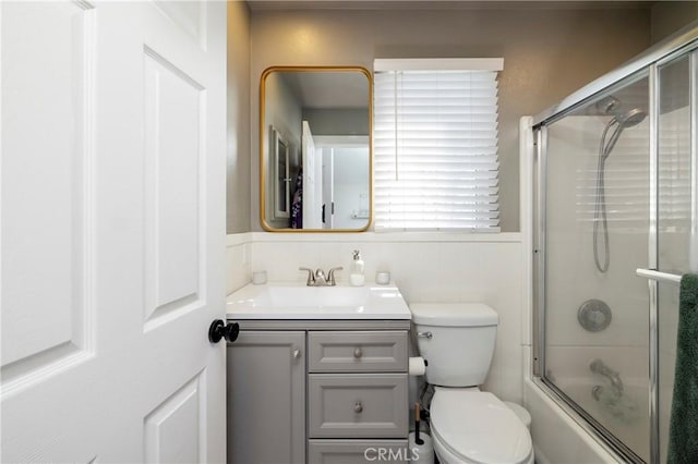 full bath with toilet, shower / bath combination with glass door, and vanity