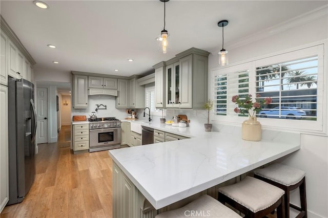 kitchen with gray cabinetry, stainless steel appliances, a peninsula, a sink, and backsplash