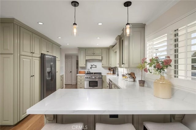 kitchen with a breakfast bar, recessed lighting, appliances with stainless steel finishes, light stone countertops, and a peninsula