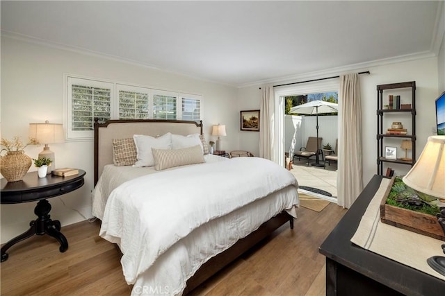 bedroom featuring access to outside, ornamental molding, and wood finished floors