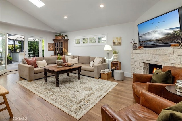 living area featuring wood finished floors, a stone fireplace, french doors, high vaulted ceiling, and recessed lighting