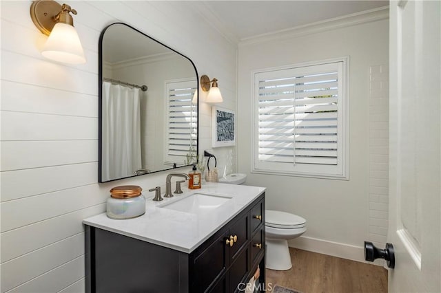 bathroom featuring baseboards, toilet, wood finished floors, crown molding, and vanity