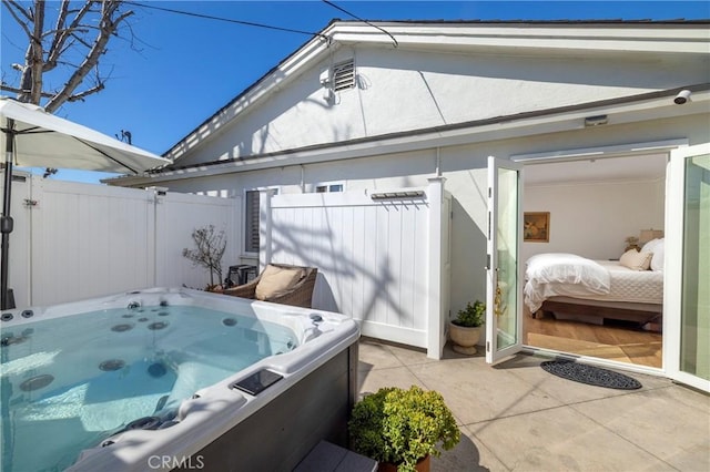 exterior space with a patio, stucco siding, fence, and a hot tub