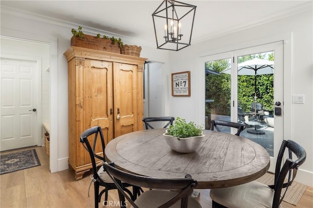 dining space with light wood-style floors, a chandelier, and crown molding