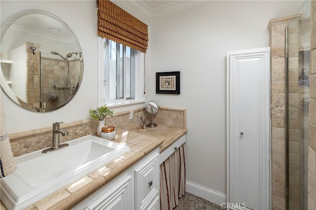 bathroom with ornamental molding, tiled shower, vanity, and baseboards