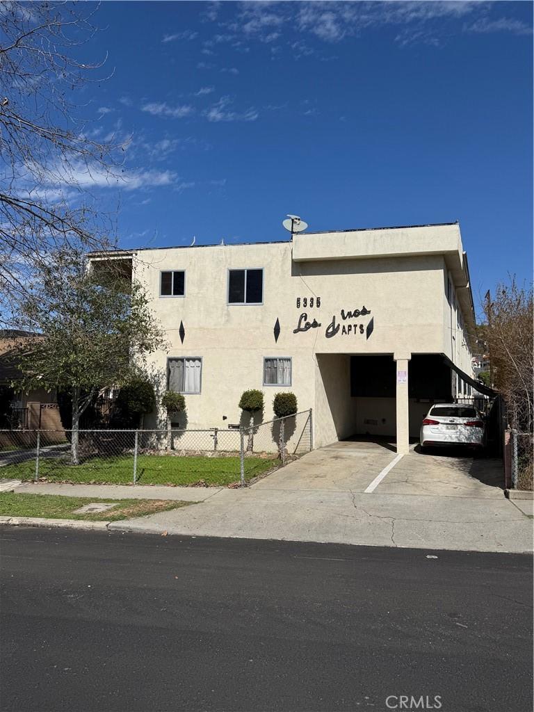 view of building exterior with uncovered parking and fence