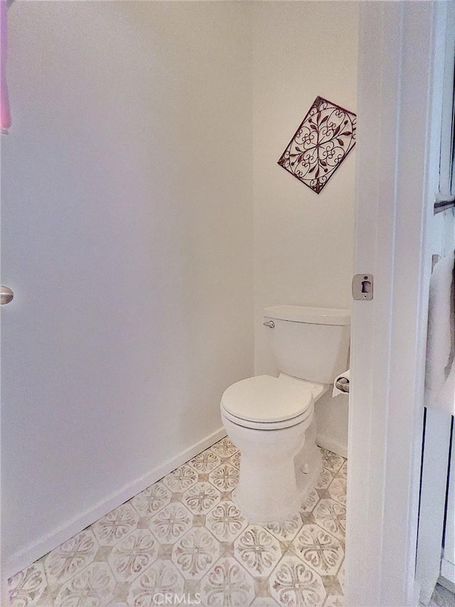 bathroom featuring tile patterned flooring, toilet, and baseboards