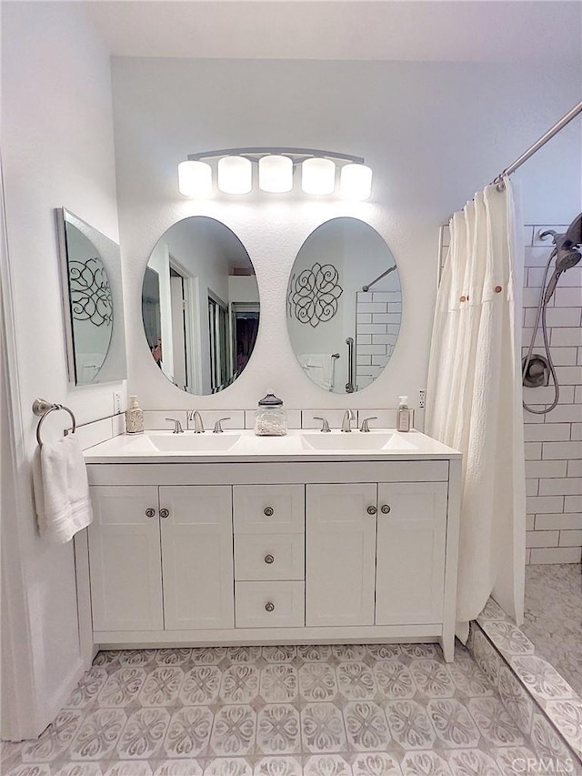 bathroom featuring a tile shower, double vanity, tile patterned flooring, and a sink