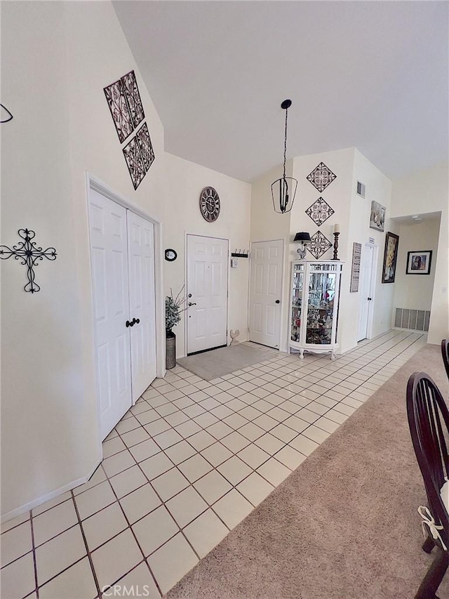 unfurnished dining area with light carpet, a high ceiling, and light tile patterned floors