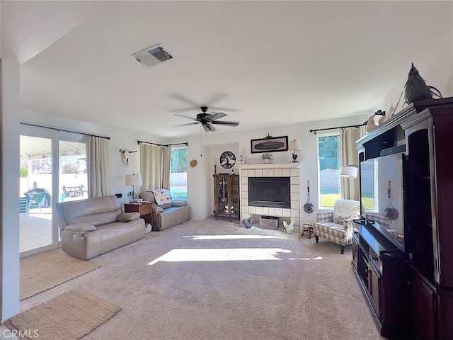 carpeted living area featuring a fireplace, visible vents, and a ceiling fan